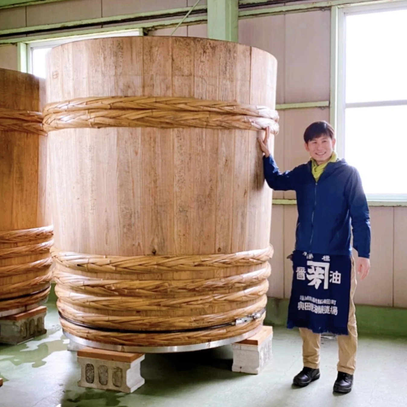 A Kaneyoshi maker beside a traditional wooden brewing barrel